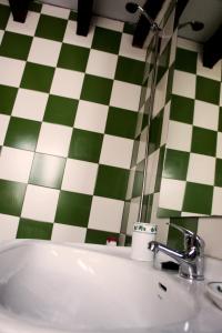 a bathroom with a sink and a green and white checkered wall at Penthouse duplex in center in Seville +7 photos