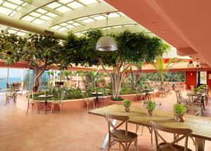 a restaurant with tables and chairs and trees in it at Out Of The Blue Resort & Spa in Agia Pelagia