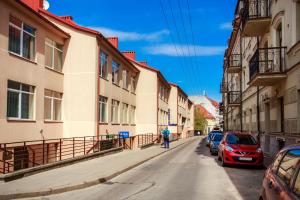 a man walking down a street next to buildings at Old Town Trio Hostel Rooms in Vilnius