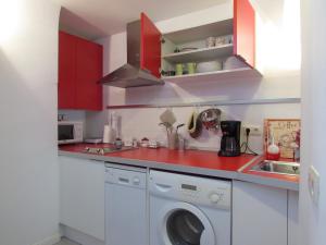 a kitchen with red cabinets and a washing machine at Apartamentos La Machacona Plaza de Santiago in Cáceres