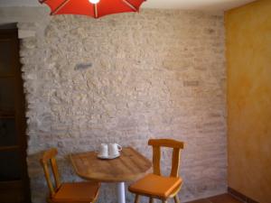 a table with two chairs and a red umbrella at Chambre d'hôte Au col de Cygne in Blanzac-lès-Matha