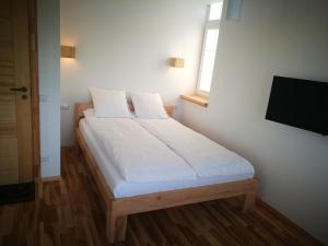 um quarto com uma cama com lençóis brancos e uma janela em Klevas em Karklė