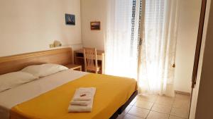 ベッラーリア・イジェア・マリーナにあるHotel Le Pleiadiのベッドルーム1室(黄色いベッド1台、タオル2枚付)