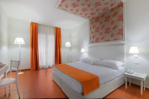 a bedroom with a bed and a table and a chair at Hotel Caparena in Taormina
