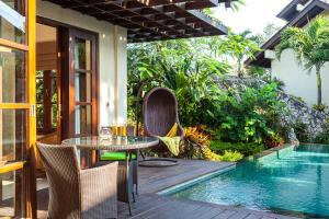 a patio with a table and chairs next to a swimming pool at Ungasan Beach Villas in Uluwatu