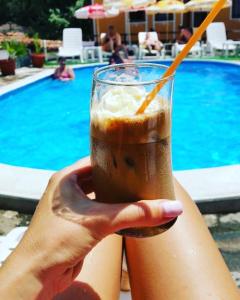 a person holding a drink in front of a pool at Guest House Todorini kashti in Koprivshtitsa
