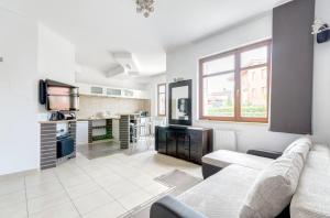 Una sala de estar con un sofá y una cocina. en Dom & House - Apartamenty Neptun Park, en Gdansk