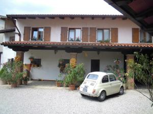 una piccola auto bianca parcheggiata di fronte a una casa di B&B Emma a Torreano
