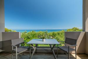 a table and chairs on a balcony with a view of the ocean at Fiore Beach Studios in Vasilikos