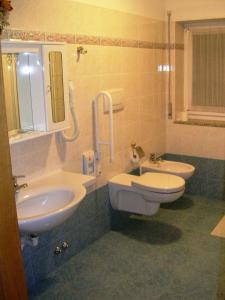 a bathroom with two sinks and a toilet and a mirror at Hotel Miramonti in Bedollo