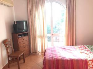 a bedroom with a bed and a tv and a window at Tavira Garden- 2 bedrooms-2pools-2 balconies in Tavira