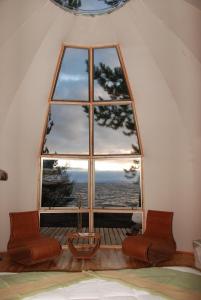 Cette chambre dispose d'une grande fenêtre avec 2 chaises. dans l'établissement Magma Lodge, Pucon, à Pucón