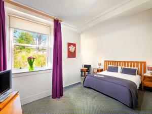 a bedroom with a bed and a window with purple curtains at Mulranny Park Hotel in Mulranny