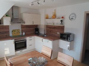 a kitchen with white cabinets and a table with chairs at Haus Maruna in Schauenburg