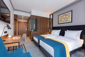 a hotel room with two beds and a desk at Grand Ascot Hotel in Krakow