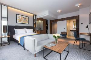 a hotel room with a bed and a couch and a table at Grand Ascot Hotel in Krakow