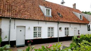 een wit huis met een rood dak bij B&B De Swaenhoeck in Damme