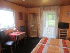 a bedroom with a bed and a table and a bathroom at Pension Talblick in Höchst im Odenwald