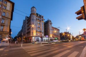 an empty city street at night with a large building at Hotel Golden Park Budapest in Budapest