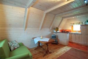 a room with a table and a green couch and a kitchen at Bajeczne domki in Ustka