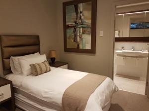 a bedroom with a white bed and a sink at Zimbali Suites 304 in Ballito +22 photos