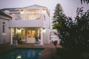 a white house with a swimming pool in front of it at The Victorian Goose in Cape Town