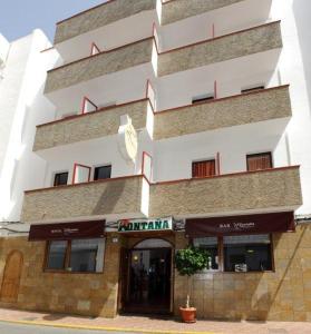 een groot wit gebouw met een bord ervoor bij Hostal Montaña in San Antonio