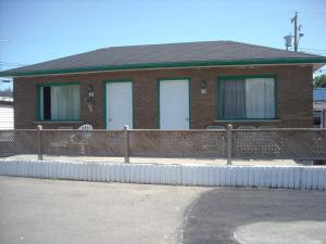 una casa de ladrillo con puertas blancas y una valla en Motel Montreal en Notre-Dame-de-l'Île-Perrot