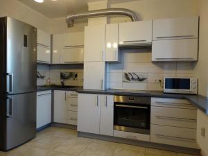 a kitchen with white cabinets and a stainless steel refrigerator at Apartment-studio Katerina in Brest