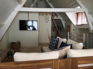 a living room with white furniture and a loft at bednextdoor in Middelburg