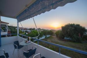 einen Balkon mit einem Tisch und Stühlen sowie einem Sonnenuntergang in der Unterkunft Dimitra Apartment Hotel in Skafidia