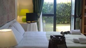 a bedroom with a white bed with a large window at Green house Marco Simone Golf Club in Marco Simone