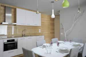 a kitchen with a white table and chairs and a kitchen with white cabinets at Apartments Etruska in Santa Cristina in Val Gardena