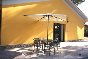 a table and chairs with an umbrella in front of a building at La Fattoria di Tirrenia in Tirrenia