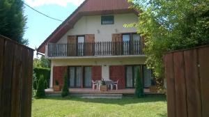 a house with a balcony and a fence at Kiss Apartman in Balatonberény