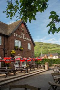 un grupo de mesas y sombrillas frente a un edificio en The Twelve Knights en Port Talbot