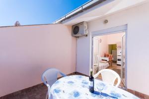 einen Tisch mit Stühlen und eine Flasche Wein darauf in der Unterkunft Apartman Anamarija in Trogir