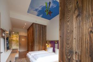 a bedroom with a bed and a wooden wall at Explorer Hotel Hinterstoder in Hinterstoder