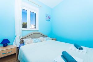 ein blaues Schlafzimmer mit einem Bett und einem Fenster in der Unterkunft Apartman Anamarija in Trogir