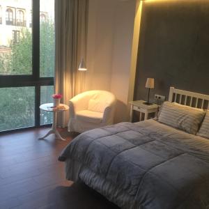 コルドバにあるBoulevard Suite Cordobaのベッドルーム1室(ベッド1台、椅子、窓付)