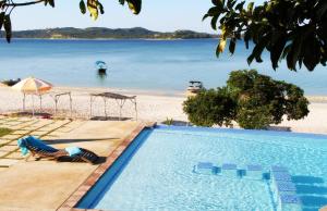 a woman laying in a chair by a swimming pool next to a beach at Bilene Lodge by Dream Resorts in Vila Praia Do Bilene