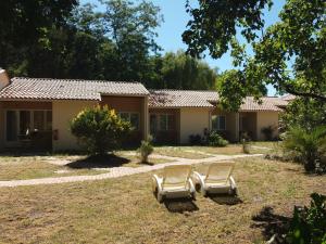 una casa con dos sillas en el patio en Acacias Hôtel Motel, en Vendays-Montalivet