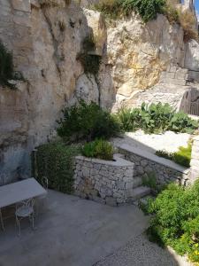 un giardino con parete in pietra e panca di Casa Ronco Scalzo a Palazzolo Acreide