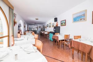 un comedor con mesas y sillas blancas en Hotel Blason Junior, en Peñíscola