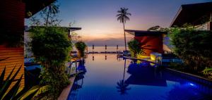 a swimming pool with a view of the ocean at sunset at Aava Resort and Spa in Khanom