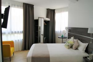 une chambre d'hôtel avec un lit et une chaise jaune dans l'établissement Appart' Hotel La Girafe Marseille Est - Porte d'Aubagne, à La Penne-sur-Huveaune