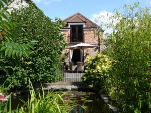 un jardin avec un étang en face d'une maison dans l'établissement Liongate House, à Ilchester