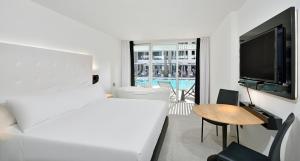 a bedroom with a bed and a television and a table at INNSiDE by Meliá Palma Bosque in Palma de Mallorca