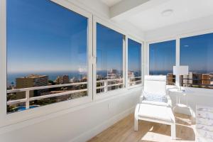 Jest to biały pokój z dużymi oknami i białym krzesłem. w obiekcie weforyou Two Rooms Terramar Alto with Sea View w mieście Benalmádena