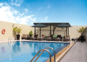 a large swimming pool with chairs and umbrellas at Al Khoory Hotel Apartments Al Barsha in Dubai